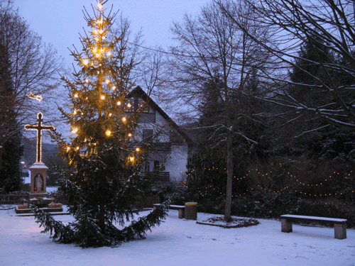 Beleuchtetes Dorfkreuz im Winter.